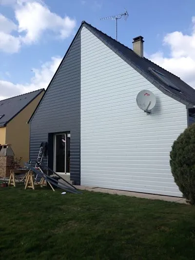 Pignon de maison habillé d'un bardage horizontal clair et gris foncé, avec baie vitrée