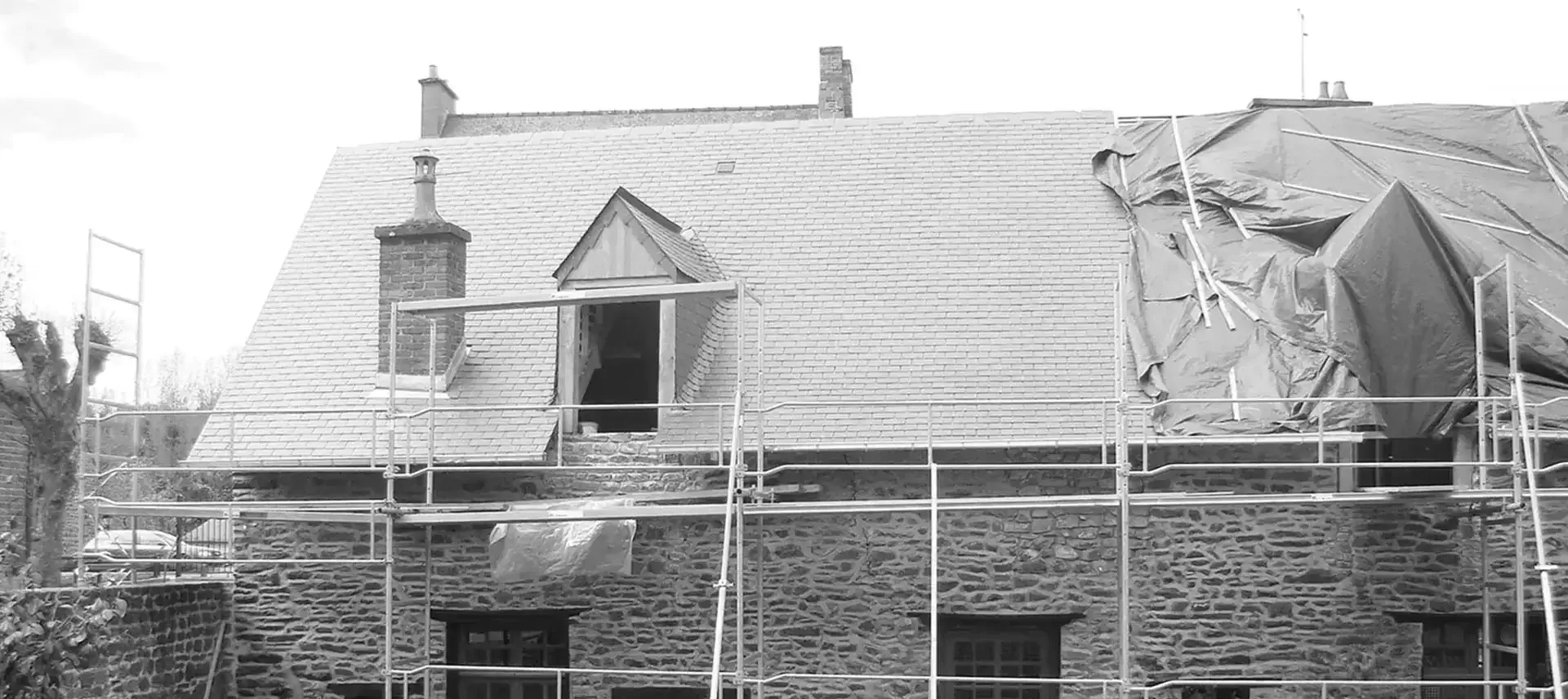 Maison ancienne en pierre sous échafaudage pendant la rénovation de sa toiture